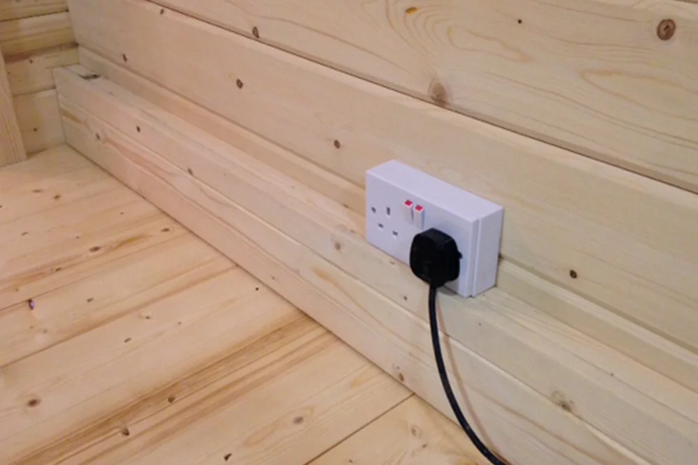 Electrical plug installed in a wooden log wall.